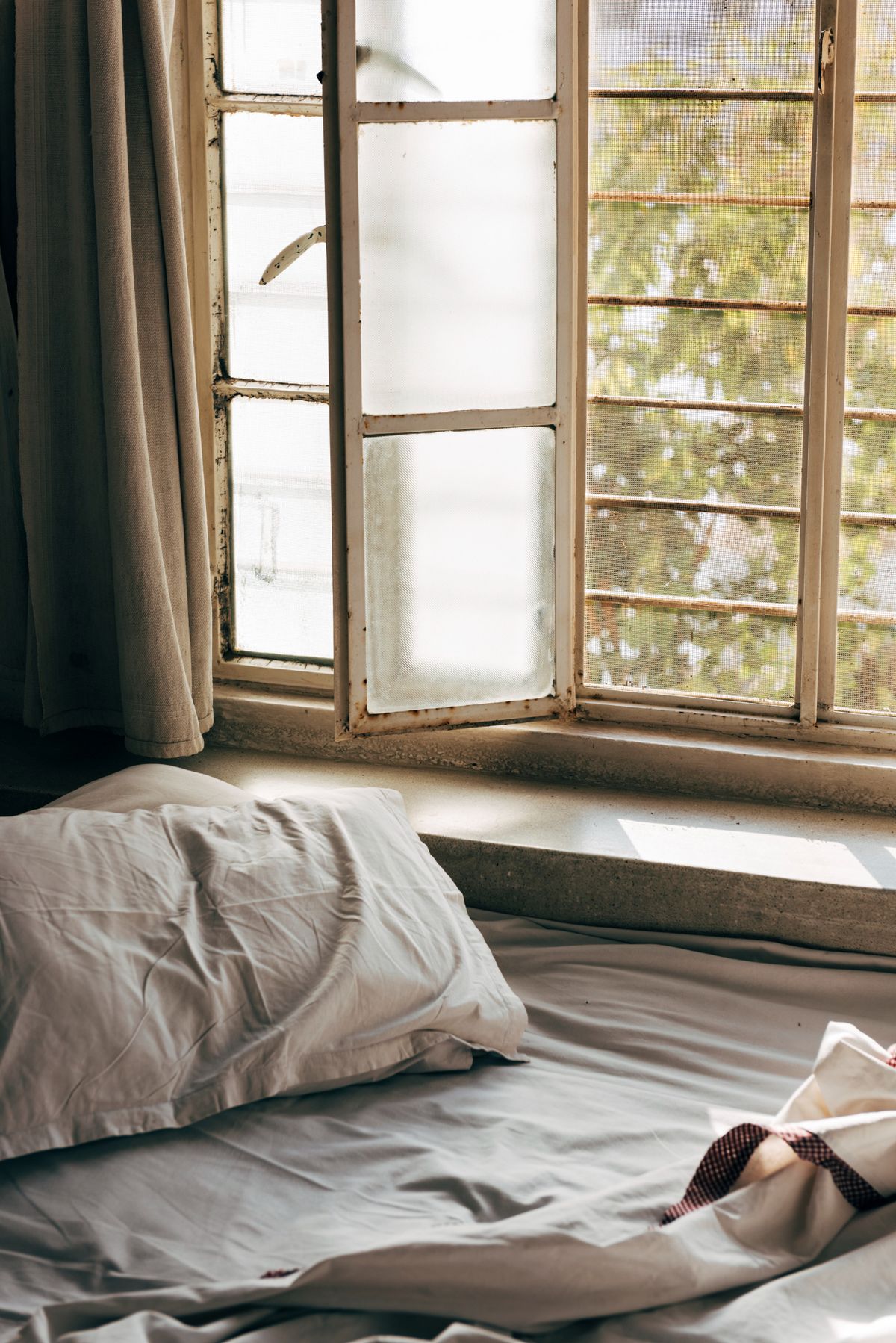 Lit défait dans la lumière du matin, fenêtre ouverte